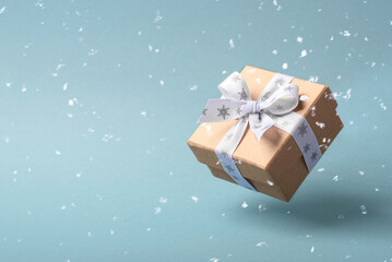 Flying Christmas gift box and snow on blue background.