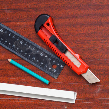 Construction or stationery knife, pencil and ruler on the board. View of the tools