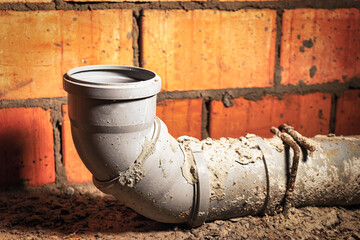 Sewer pipes in home basement. System of gray sanitary pipes when building a house. Sewer...
