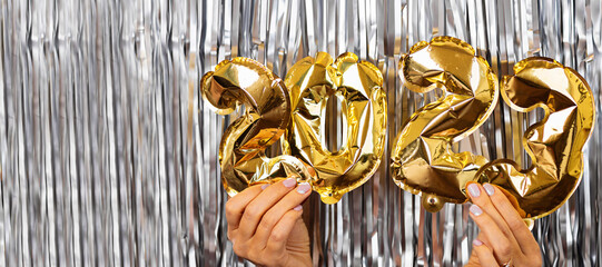 Merry Christmas and Happy new year 2023 background. Winter holiday celebration mockup with golden foil numbers in hand. Horizontal banner for web design with copy space