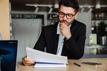 Young businessman in formal wear working with papers in office