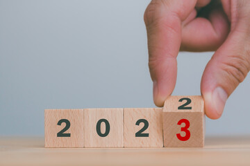Started and begin of the new year 2023. Happy new year,new life,new business,plan,goals,strategy concept,preparation count down and hand flips wooden cubes with 2022 change to 2023 on smart background