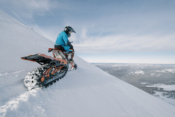 Snowbike rider on steep snowy slope. Modify motorcycle with ski and special snowmobile-style track...
