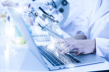 Close-up view of a scientist or student using a laptop computer and a microscope. science concept