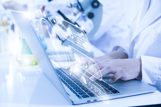 Close-up view of a scientist or student using a laptop computer and a microscope. science concept