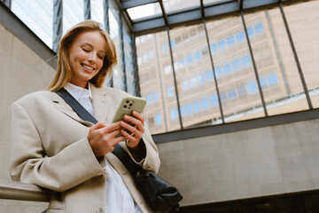 Young beautiful smiling happy woman holding and using her phone