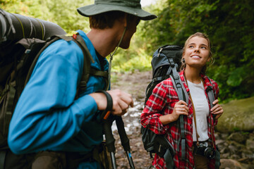 White young travelers with backpacks hiking together in forest