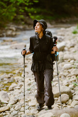 Happy white woman using trekking pole while hiking in forest