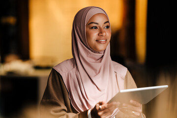 Arabian woman working on tablet while standing indoors