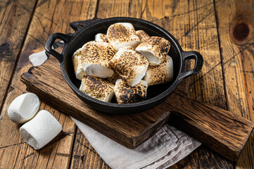 Toasted Marshmallow on open campfire in a skillet. Wooden background. Top view