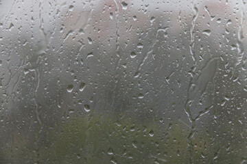 Raindrops drip down on the window glass. Soft selective focus.