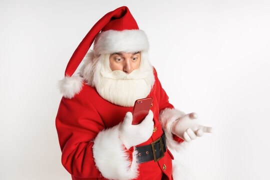 Funny Santa in a headdress, suit, black belt, white gloves, prepares to celebrate. Sale promotion, winter December, communication by phone. White background.
