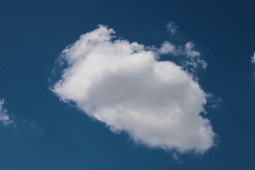 blue sky with clouds A single low floating cloud stands out in the middle of the blue sky contrasting with the white clouds.