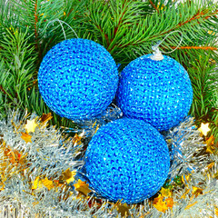 A sprig of fir, blue Christmas balls and tinsel background.