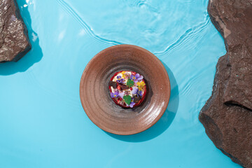 Ceramic bowl with blue clear water with flowers salad