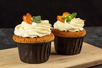 Cupcakes with cheese cream decorated with berries on dark background