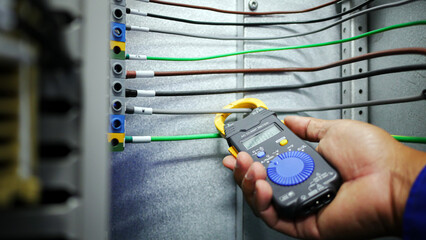Hand closeup of electrical engineer to use digital ampere meter to measurement electrical current...