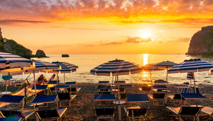 morning or evening landscape with nice beach with deck chairs and umbrellas during sunrise or sunset with amazing sea with rocks and beautiful clouds on background