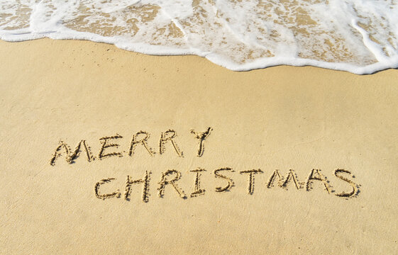 Merry Christmas handwritten in sand on beach