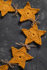 Handmade Christmas decoration on a grey background. Crochet yellow stars garland close up. Christmas craft.