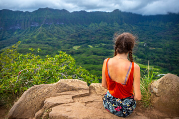 hiker girl stands at the top of olomana ridge trail admiring the panorama of oahu and hawaii mountains; famous three peaks on oahu, dangerous hiking on hawaii mountains, hawaii holidays