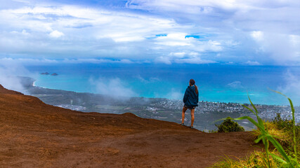 girl in pigtails stands at the top of the kuliouou ridge trail admiring the panorama of oahu,...