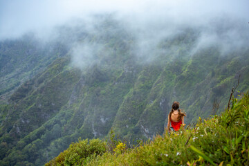 girl in pigtails stands at the top of the kuliouou ridge trail admiring the panorama of oahu, honolulu and the hawaiian mountains; hiking in the mountains in hawaii, holiday in hawaii