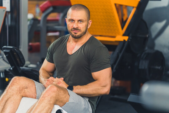Strong, muscular, handsome bald man, bodybuilder, performing abs crunches on the decline bench in the gym, resting before sets. High quality photo
