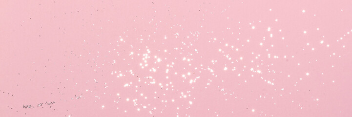 Sparkling silver glitter on pink background banner texture. Abstract holiday blurred lights header. Wide screen wallpaper. Panoramic web banner with copy space for design