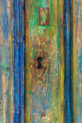 Keyhole on an old door covered with many layers of colorful paint