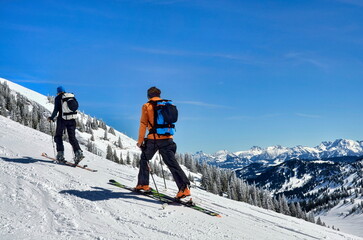 Zwei Skitourengeher, Skibergsteiger im Aufstieg mit Aussicht auf Bergpanorama in den Alpen
