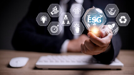 Businessman hand holding light bulb with esg icon on virtual screen, ESG Environmental, social and corporate governance concept