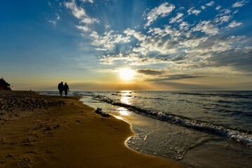 Fototapeta Zachód słońca z parą zakochanych spacerującą po plaży  obraz