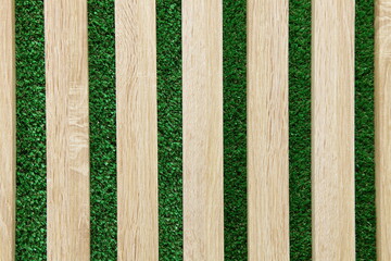 Wooden horizontal panels of natural color on the background of artificial green grass. A texture with space to copy.