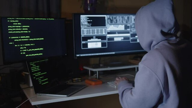 Young hacker, working and hacking with his computers. Attacking systems and danger computering.