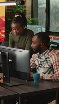 Vertical video: African american team of people looking at cad software on pc, analyzing manufacturing interface with 3d infographics. Man and woman working on industry development in creative agency.