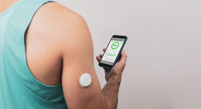 Unrecognizable back young man shows his mobile with continuous glucose monitor blood sugar test app, glucose measurement.Copyspace