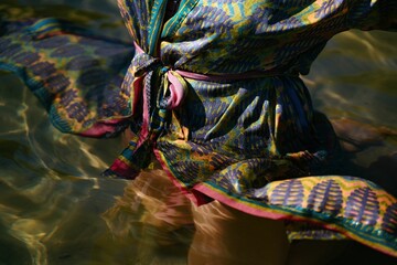 Woman wearing a fabric silk bathrobe half submerge in the water