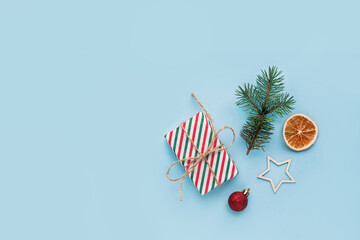 Christmas composition with eco crafted gift, dried orange, cone, xmas tree fir branch, gift and wood star. Natural minimal new year concept, top view, flat lay, isolated, copy space on red background