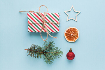 Christmas composition with eco crafted gift, dried orange, cone, xmas tree fir branch, gift and wood star. Natural minimal new year concept, top view, flat lay, isolated, copy space on red background