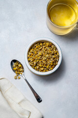 Dry chamomile flowers tea on bright background, herbal plants