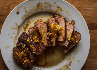 Tasty juicy roast pork tenderloin on a white plate. Overhead close-up 