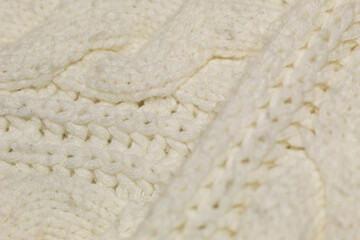 Close-up on a hand-stitched beige warm cozy fabric with a defocused part in the foreground