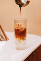 Vertical shot of espresso being poured into a tonic drink with ice.