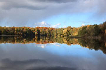 Lake with trees on the shore with yellowed foliage in autumn in sunny weather.