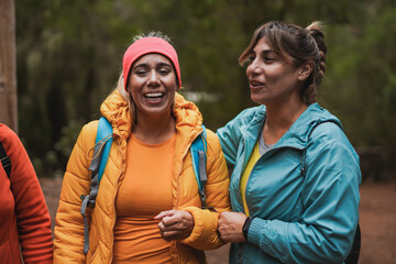Mature latin women having fun together during trekking day at mountain forest