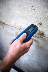 Eine Hand hält ein Messgerät zur Messung der Feuchtigkeit in einer Wand