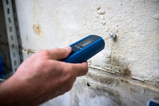 Eine Hand hält ein Messgerät zur Messung der Feuchtigkeit in einer Wand