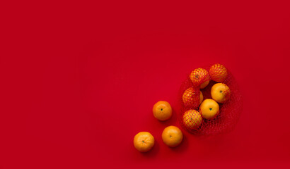Tangerines in a red grid on a red background. New Year's mood. Place of the text. Banner.