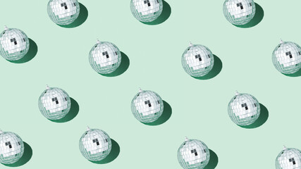Shiny silver disco balls over green background. Creative Christmas pattern. 90s retro party time...